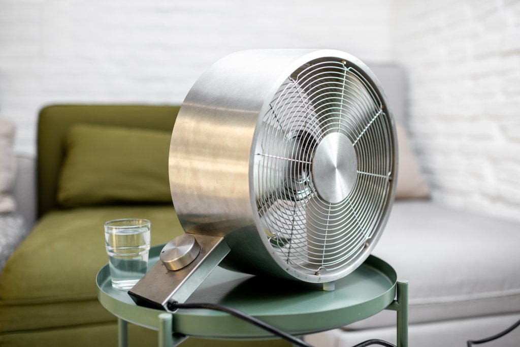 Fan with a glass of water on the table at home