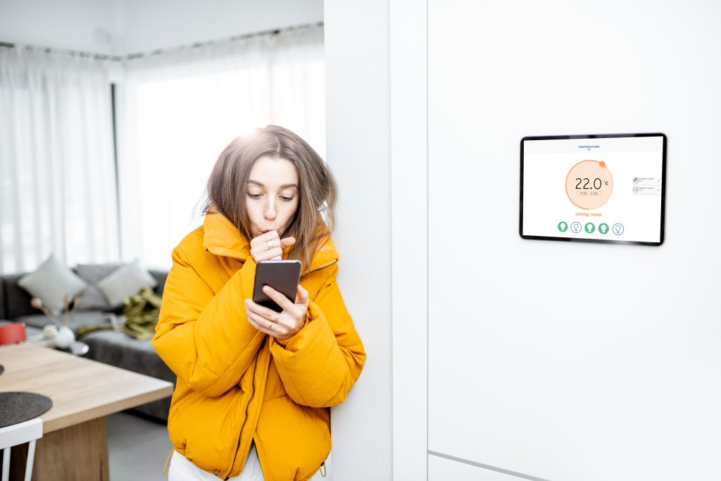 Woman feeling cold, controlling heating with a smart devices at home